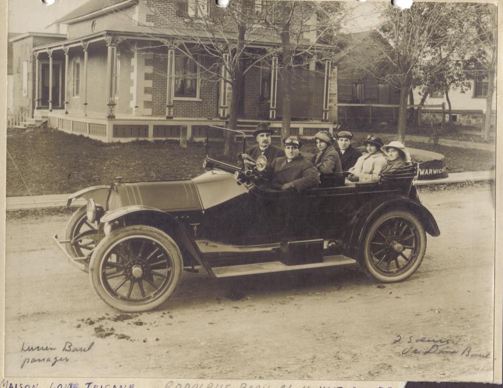 Rodolphe Baril conduisant une auto Mitchell (vers 1915 ?). Son beau-père, monsieur Médard Luneau est assis à sa droite. Au centre, madame Augustine Luneau, son épouse et à l’arrière à droite, son frère Lucien avec deux sœurs de madame Luneau.